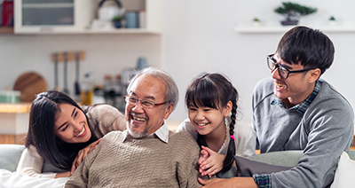 multigenerational Asian family sit on sofa couch in living room with smile. 